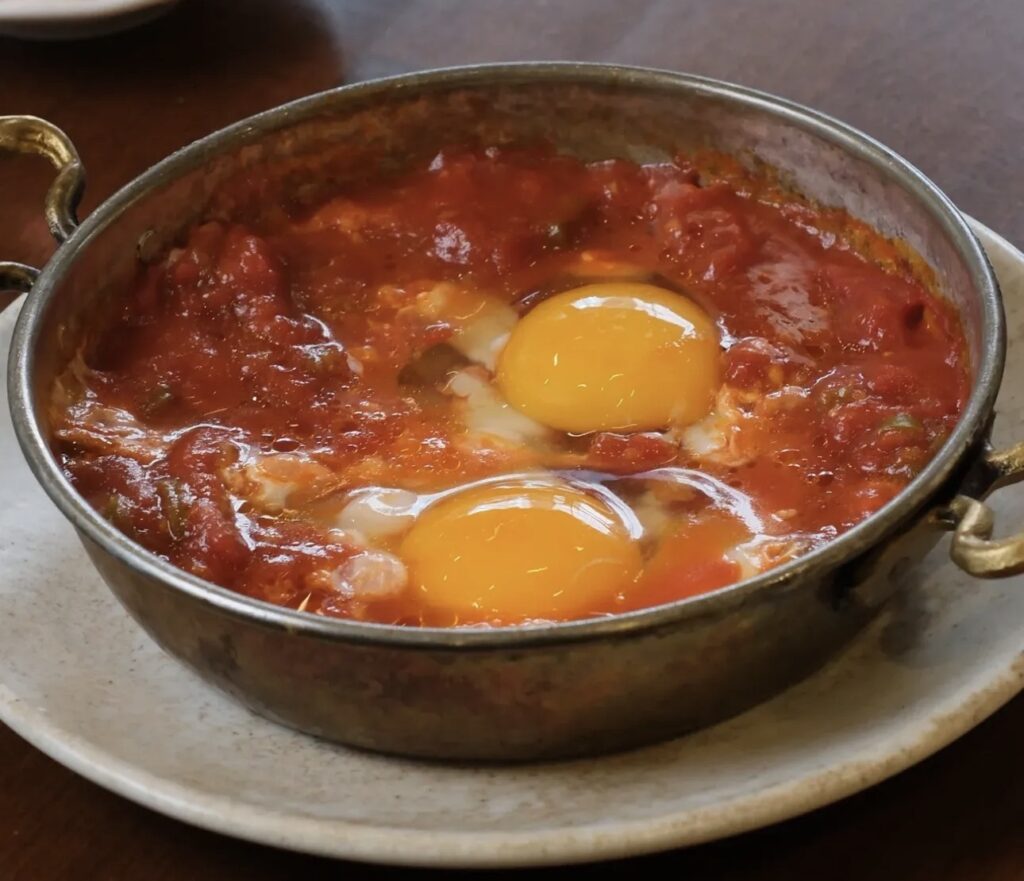 A copper pan filled with Ceviz Ev Yapımı’s famous Menemen; juicy tomatoes, green peppers, and eggs cooked to perfection.