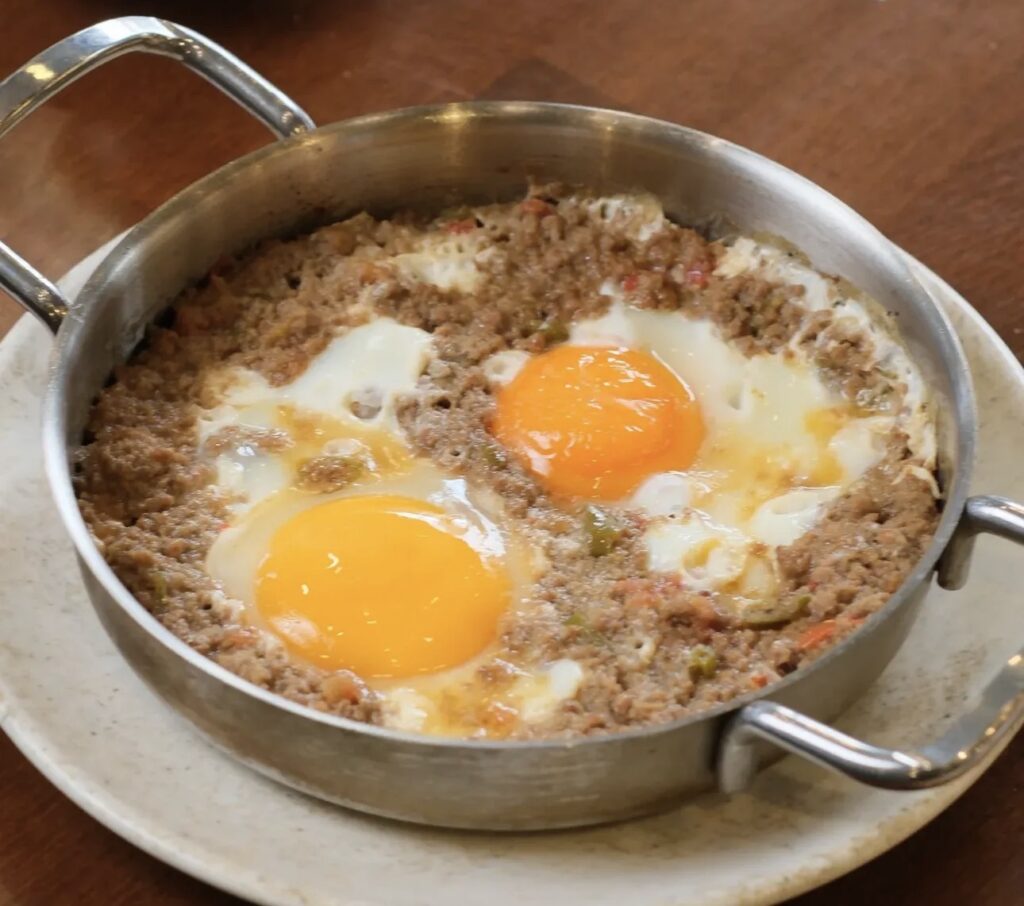 Traditional Turkish breakfast dish at Ceviz Ev Yapımı; fried eggs with minced meat served sizzling hot in a copper pan.