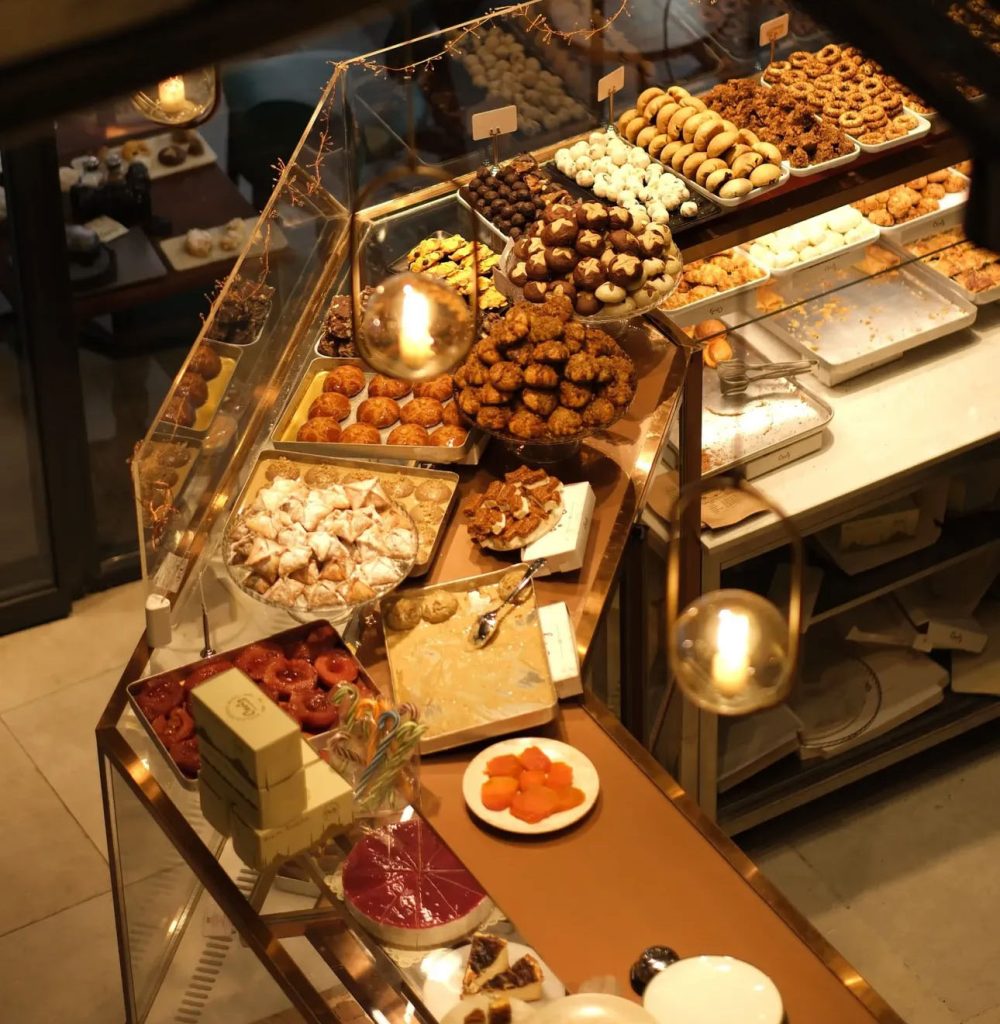 A warmly lit patisserie showcase displaying various types of handmade cookies and desserts.
